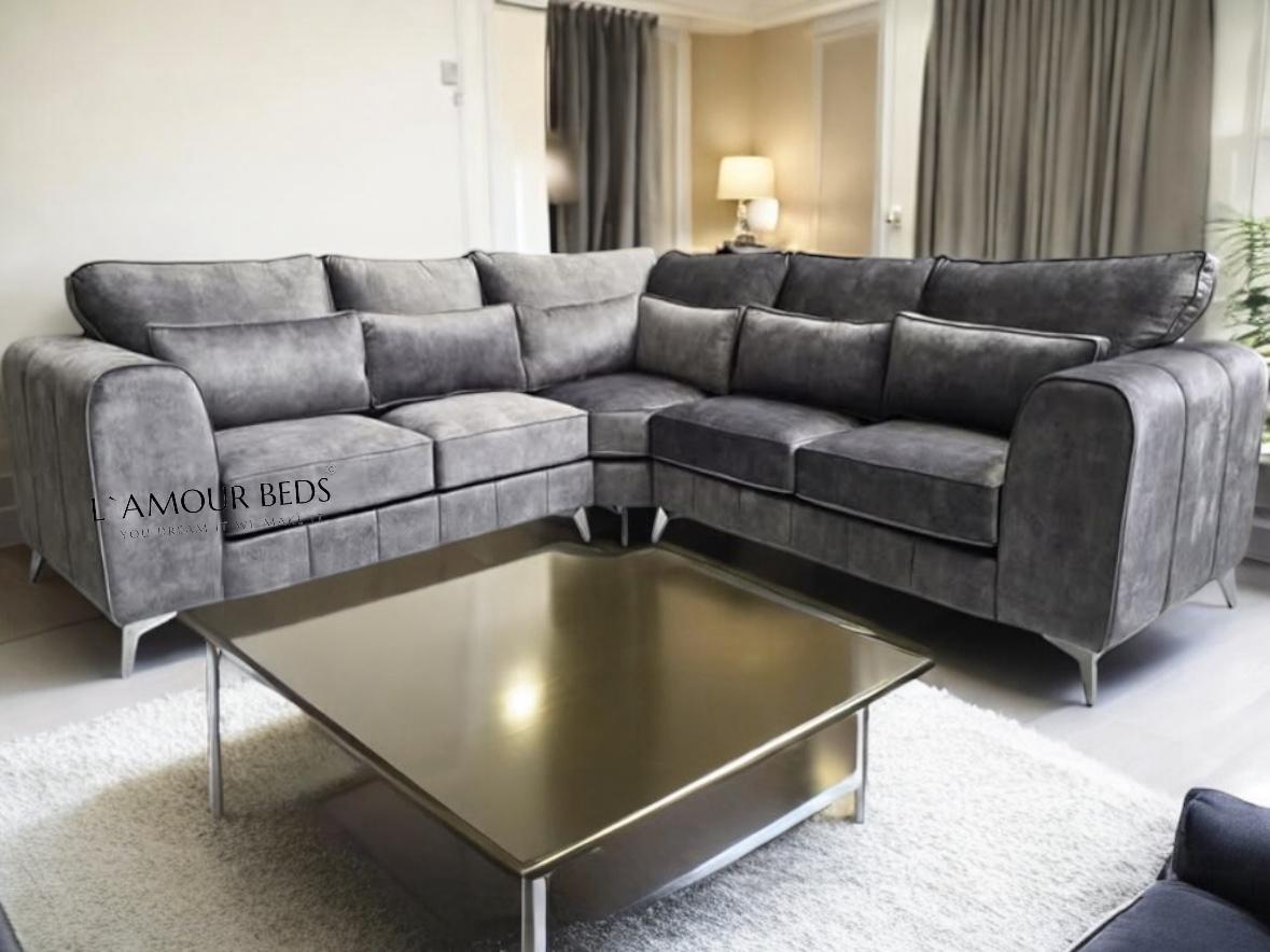 A spacious living room features a sleek gray sectional sofa on a light carpet, modern glass coffee table, soft lighting, and neutral curtains, evoking coziness.