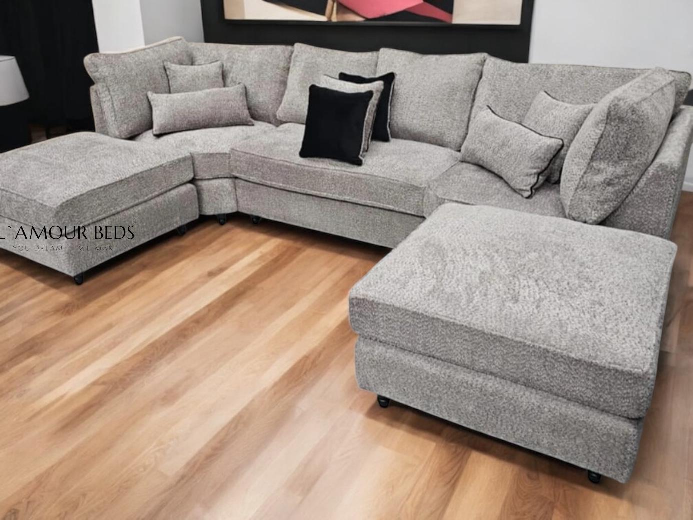 Gray L-shaped sectional sofa with black accent pillows on sleek wooden floor. Modern art on the wall enhances the cozy, elegant ambiance.